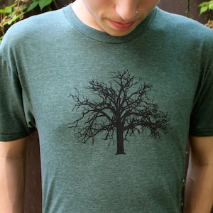 May include: A dark green t-shirt with a black silhouette of a bare tree on the front.
