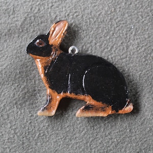 Può includere: Un ornamento di coniglio dipinto di nero e marrone con un anello d'argento per appenderlo.