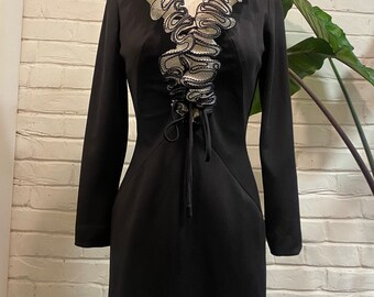 May include: A black long-sleeved dress with a white lace ruffle neckline and a lace-up detail at the front.