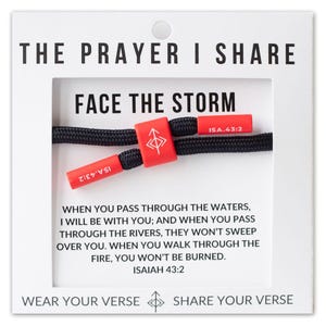 May include: Black braided cord bracelet with red accents. The bracelet features the text "FACE THE STORM" and a Bible verse. The card reads "THE PRAYER I SHARE" and "WEAR YOUR VERSE" and "SHARE YOUR VERSE".