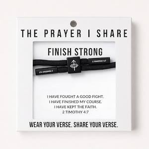 May include: A black cord bracelet featuring a square bead with an arrow symbol and two rectangular end pieces inscribed with 2 TIMOTHY 4:7. The packaging displays the text THE PRAYER I SHARE, FINISH STRONG, and the full verse 2 TIMOTHY 4:7.