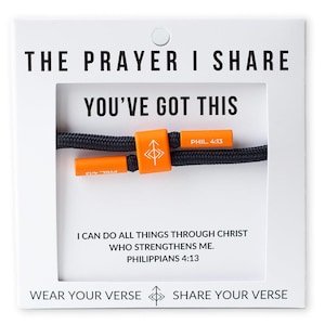 May include: A black cord bracelet with orange accents. The bracelet features the text "YOU'VE GOT THIS" and "PHIL. 4:13". The card reads "THE PRAYER I SHARE" and "I CAN DO ALL THINGS THROUGH CHRIST WHO STRENGTHENS ME. PHILIPPIANS 4:13".