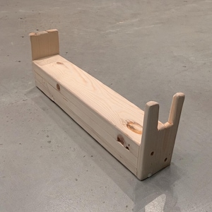 May include: A natural wood bench with a rectangular seat and two upright supports at each end. The bench is made of unfinished wood and has a simple, minimalist design. The bench is approximately 36 inches long.