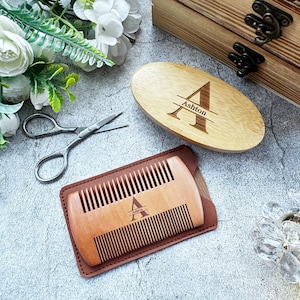 以下が含まれることがあります： 革製のケースに入った木製のコームとブラシのセット。コームとブラシの両方に「Ashton」という名前が刻まれています。