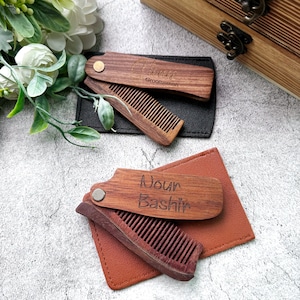 May include: Two wooden pocket combs with personalised engravings. The top comb is engraved with "Chris" and "Groomsman". The bottom comb is engraved with "Nour Bashir".