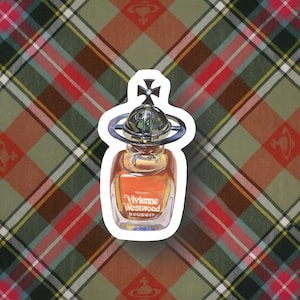 Könnte beinhalten: Eine durchsichtige Glasflasche mit Vivienne Westwood Boudoir Parfum und einem goldenen Kugelverschluss. Die Flasche steht auf einem karierten Hintergrund.