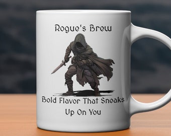 May include: White ceramic mug with a black and brown illustration of a hooded figure holding a sword. The text "Rogue's Brew" and "Bold Flavor That Sneaks Up On You" is printed on the mug.