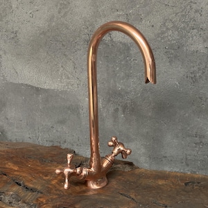 May include: A copper kitchen faucet with a high arc spout and two cross-shaped handles.