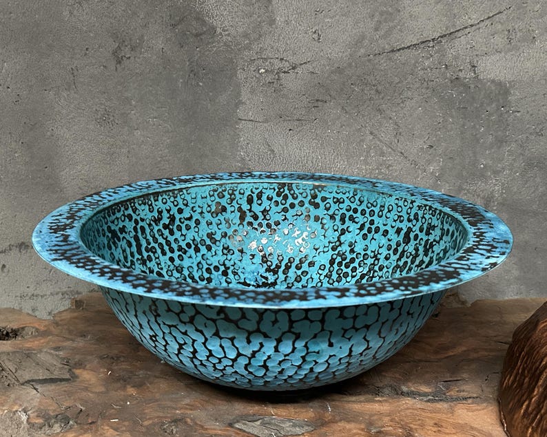 May include: A turquoise ceramic bowl with a speckled pattern. The bowl has a wide, rounded rim and a textured surface. The interior and exterior are a vibrant turquoise colour with black speckles, creating a unique design.