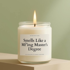 May include: A lit, white soy wax candle in a clear glass jar. The label reads "Smells Like a Mf'ing Master's Degree." The candle is hand-poured and eco-friendly.