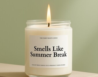 May include: A lit candle in a clear glass jar with a white label that reads "Smells Like Summer Break." The candle is labeled "The Starry Nights Candle" and is made of 100% soy wax. The candle is hand-poured and eco-friendly.