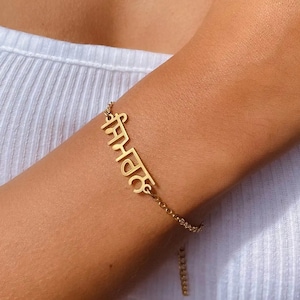 May include: A gold chain bracelet with a pendant that says "समाधान" in Hindi script.