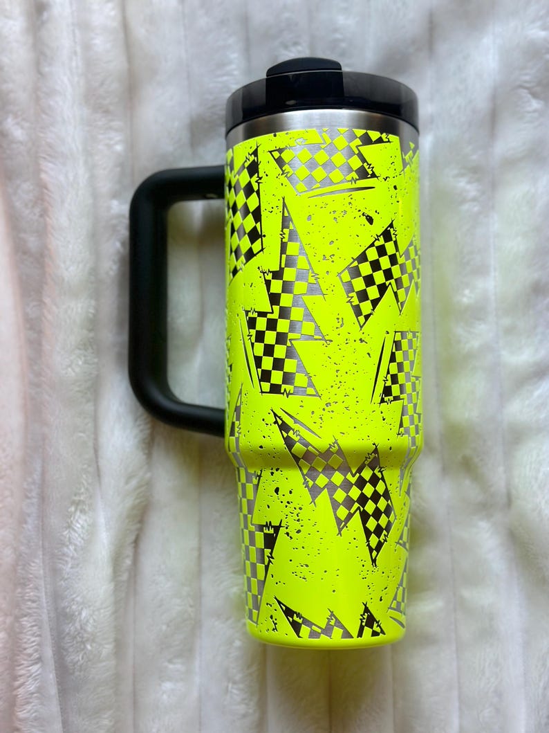 K&ouml;nnte beinhalten: Eine neon-gelbe Edelstahl-Reise-Thermoskanne mit schwarzem Griff und einem karierten Flaggenmuster.