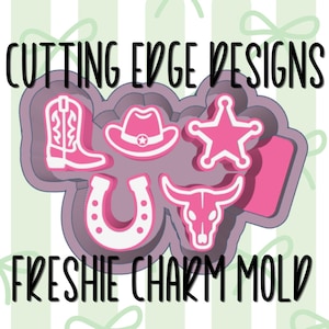 May include: A purple mold for making charms, featuring five western-themed shapes in bright pink: a cowboy boot, a cowboy hat, a sheriff star, a horseshoe, and a bull skull. The text CUTTING EDGE DESIGNS and FRESHIE CHARM MOLD is visible.