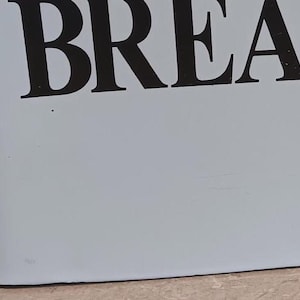 May include: White enamelware kitchen canisters with black trim and labels. The large canister is labeled "BREAD", the medium canister is labeled "TREATS", the small canister is labeled "BUTTER", and the smallest canister is labeled "SERVE".