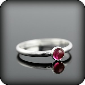 Peut inclure: Une bague simple en argent avec une seule pierre rouge ronde.