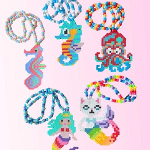May include: A selection of colourful beaded necklaces with sea creature designs. The necklaces feature a seahorse, octopus, mermaid, and cat, all made with bright beads. These handmade necklaces have a playful aesthetic, ideal for children.