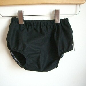 May include: Black cotton baby bloomers with an elastic waistband and ruffled legs.