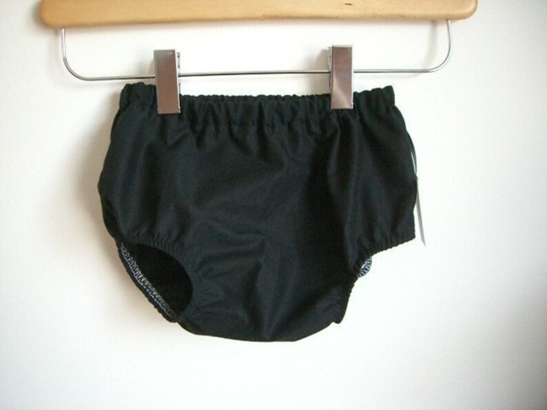 May include: Black cotton baby bloomers with an elastic waistband and ruffled legs.