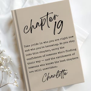 May include: A beige hardcover book featuring the text "chapter 19" in a black script font at the top, followed by a paragraph of black typewriter-style text, and the name "Charlotte" in a black script font at the bottom of the front cover.