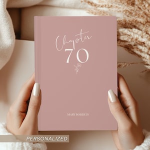 May include: A dusty rose-colored journal with the words "Chapter 70" in elegant script. The journal also features the name "Mary Roberts" and a small floral design. The word "PERSONALIZED" is at the bottom.