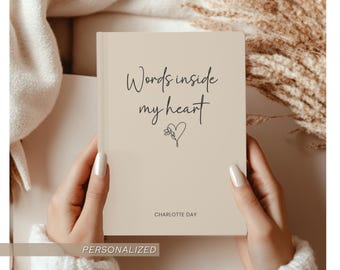 May include: A beige notebook with the words "Words inside my heart" in black script, along with a heart and flower illustration. The name "CHARLOTTE DAY" is printed at the bottom. The notebook is held by two hands.