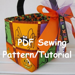 以下が含まれることがあります： ハロウィンのトリックオアトリートバッグのPDF縫製パターンとチュートリアル。バッグはオレンジ、グリーン、ブラック、パープルの生地でできており、クモ、カボチャ、ゴーストのデザインが施されています。バッグには黒いハンドルと明るいオレンジのリボンが付いています。