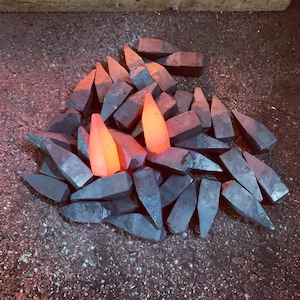 Op de afbeelding: Een stapel metalen stukken, waarvan sommige oranje gloeien, zijn in een willekeurig patroon gerangschikt. De metalen stukken zijn allemaal van verschillende vormen en maten.