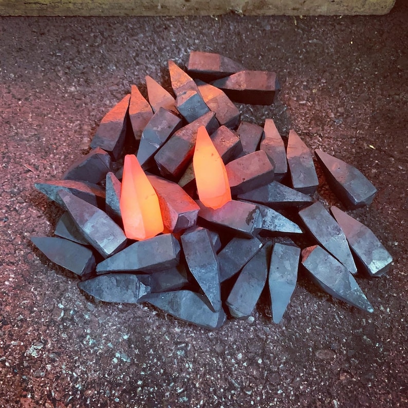 Op de afbeelding: Een stapel metalen stukken, waarvan sommige oranje gloeien, zijn in een willekeurig patroon gerangschikt. De metalen stukken zijn allemaal van verschillende vormen en maten.