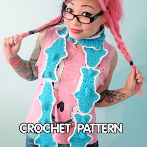 May include: A blue and white crocheted scarf with a fish design. The scarf is worn by a person with pink hair and a pink shirt. The text "CROCHET PATTERN" is visible at the bottom of the image.