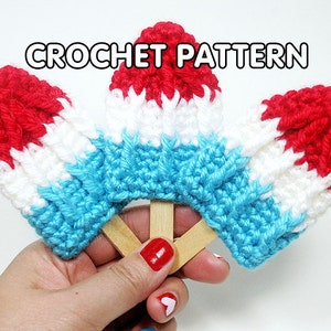 May include: Three crocheted popsicles in red, white, and blue colors, resembling an American flag. The popsicles are attached to wooden sticks.