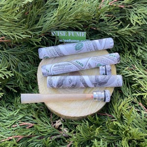 Puede incluir: Cuatro pipas para fumar con temática de dinero con un diseño blanco y verde. Las pipas están hechas de un material duradero y tienen un aspecto elegante y moderno. Las pipas están dispuestas sobre una superficie de madera con un fondo verde.