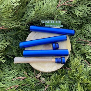 May include: Three blue metal tubes with a screw-on cap. The tubes are on a wooden surface and a brown paper tube is partially inside one of the tubes. The text "WISE FUME" and "wisefume.com" is on a white label.