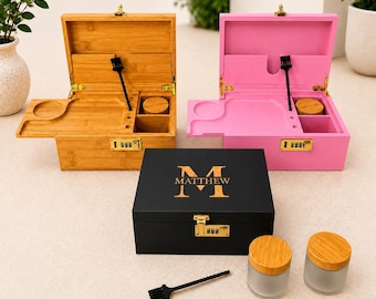 May include: Three wooden boxes, one bamboo-colored, one pink, and one black, are displayed open and closed. The black box has "M MATTHEW" in gold lettering. Each box has a combination lock and a small tool. Two glass jars with wooden lids are also present.
