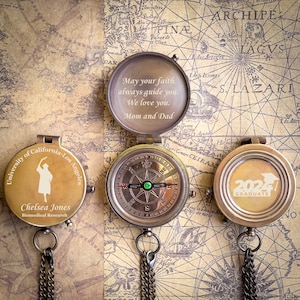 May include: Three antique brass compass-style boxes with engraved messages. The top box reads "May your faith always guide you. We love you. Mom and Dad". The middle box has a compass face with a green jewel at the center. The bottom box reads "2021 Graduate".