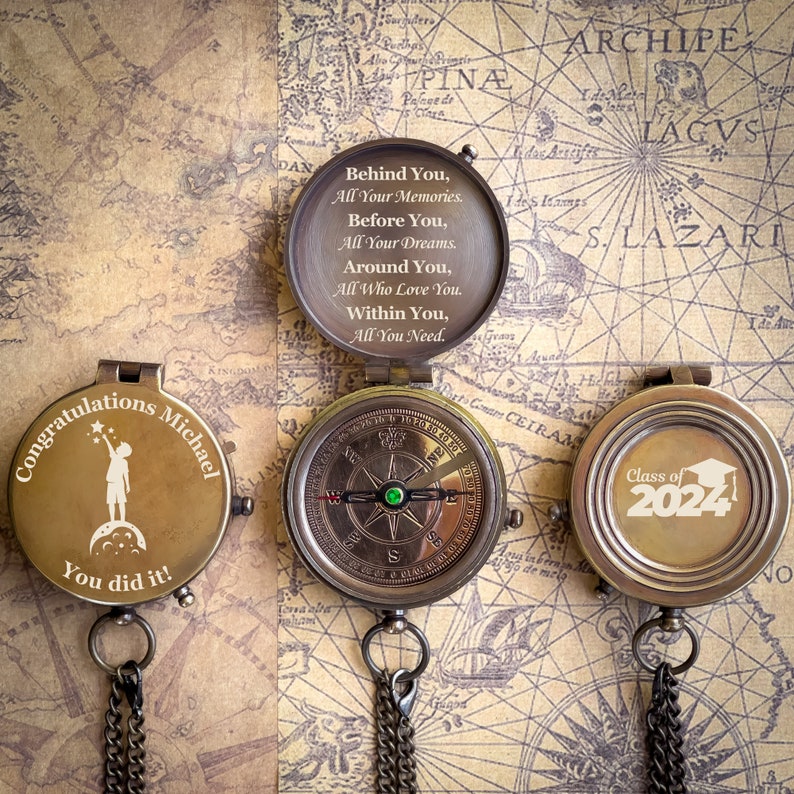 May include: Three antique brass compasses with chains are displayed on a vintage map background. One compass is open, revealing an inspirational quote. The other two compasses have custom text: "Congratulations Michael, You did it!" and "Class of 2024".
