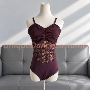 May include: A dark burgundy leotard featuring a ruched lace bodice, thin shoulder straps, and a sheer lace midsection with vertical boning details. The garment includes the text UniqueDanceCostume overlaid across the center.