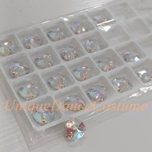 May include: A clear plastic container filled with iridescent round rhinestones. The container is labelled "Unique Dance Costume".