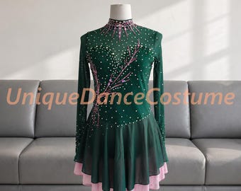 May include: A dark green long-sleeve dance costume featuring a high neckline, sheer mesh fabric, and a layered skirt with a light pink underskirt. The bodice is embellished with scattered white crystals and pink floral-like patterns. UniqueDanceCostume.