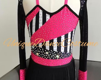 May include: A dance costume with a black and white striped bodice, accented with pink and embellished with rhinestones. The costume features a black fringe skirt and long sleeves with pink cuffs. The text "Unique Dance Costume" is visible.