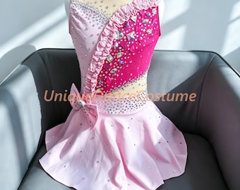 May include: A sleeveless dance costume featuring a light pink and hot pink bodice with a sheer mesh neckline, adorned with scattered crystals, a ruffled diagonal trim, and a side bow. The skirt is light pink with scattered crystal embellishments.