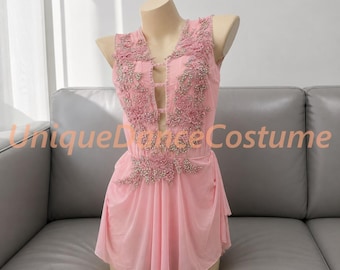 May include: A light pink sleeveless dance costume featuring a deep V-neckline with horizontal straps, adorned with floral lace appliques and clear rhinestones. The text UniqueDanceCostume is visible across the center of the garment.