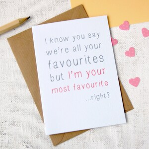 White background, with craft envelope and white A6 greeting card reading i know you say we are all your favourites but im your most favourite...right? Writing is in grey except for im your most favourite which is in a rose pink