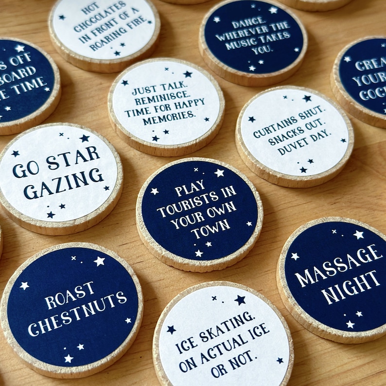 Twenty four wooden tokens, each with a recycled label that have a date night idea printed on, lay on a wooden desk.