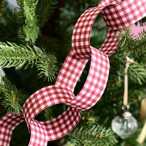 Red gingham Christmas paper chains are looped around a decorated tree, with traditional and handmade Christmas decorations hanging beside them.