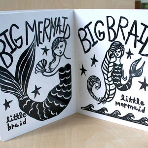 K&ouml;nnte beinhalten: Ein schwarz-wei&szlig; illustriertes Kinderbuch mit dem Text "Big Mermaid, Big Braid" auf dem Cover. Die linke Seite zeigt eine Meerjungfrau mit einem gro&szlig;en Schwanz und dem Text "little braid". Die rechte Seite zeigt eine Meerjungfrau mit einem langen Zopf und dem Text "little mermaid".