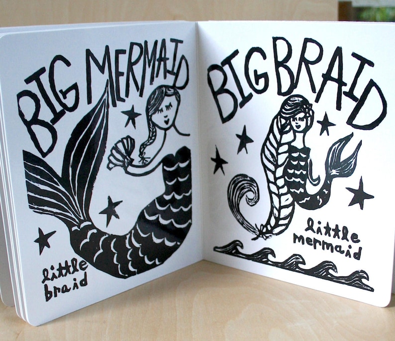 K&ouml;nnte beinhalten: Ein schwarz-wei&szlig; illustriertes Kinderbuch mit dem Text "Big Mermaid, Big Braid" auf dem Cover. Die linke Seite zeigt eine Meerjungfrau mit einem gro&szlig;en Schwanz und dem Text "little braid". Die rechte Seite zeigt eine Meerjungfrau mit einem langen Zopf und dem Text "little mermaid".