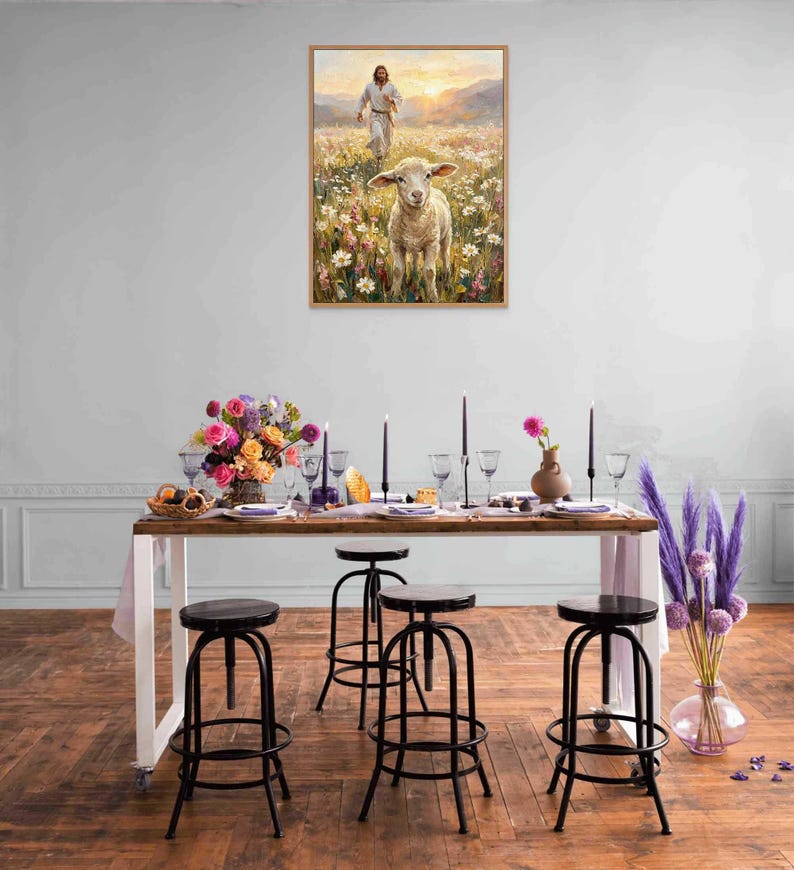 K&ouml;nnte beinhalten: Ein gerahmtes Gem&auml;lde zeigt ein Lamm in einem Blumenfeld mit einer Figur im Hintergrund. Ein langer Holztisch ist mit Kerzen, Blumen und Glaswaren gedeckt. Schwarze Metallhocker mit runden Sitzen sind um den Tisch herum aufgestellt.