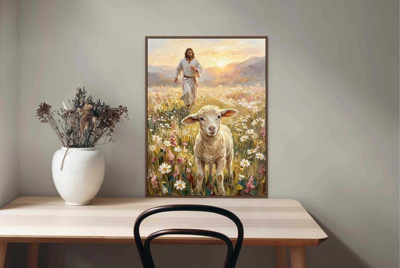 K&ouml;nnte beinhalten: Gerahmtes Kunstwerk, das eine Figur in wei&szlig;en Gew&auml;ndern zeigt, die durch ein Feld mit Wildblumen auf ein Lamm zugeht. Das Gem&auml;lde hat eine warme Farbpalette mit einem Sonnenuntergang im Hintergrund. Das Kunstwerk wird auf einem hellen Holztisch ausgestellt.