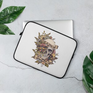 Op de afbeelding: Witte laptophoes met een zwarte rits. De hoes heeft een schedel met bloemen en vlinders. De tekst "Wees bang en doe het toch" staat op een banner.